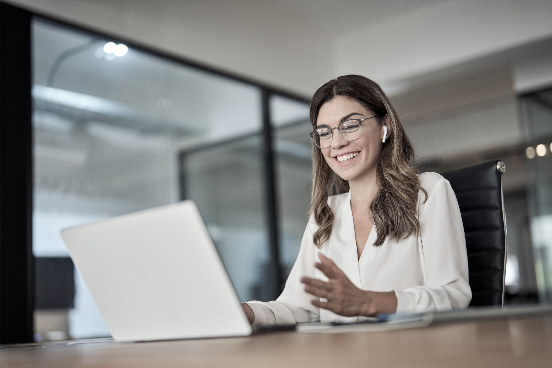 A business woman seated at a desk, working on a laptop computer.