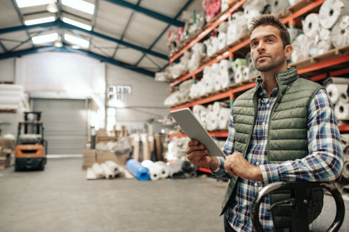 General Liability Insurance in MN - A man in a warehouse holding a tablet computer.