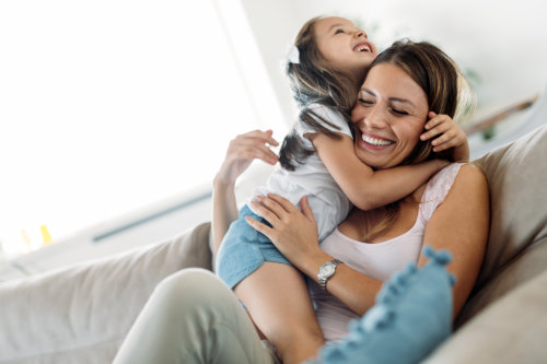 Life insurance in MN - A woman hugging her daughter on a sofa.